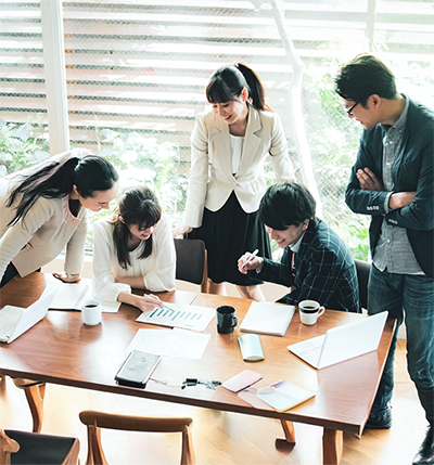 ５人のビジネスマンが相談しながらプロジェクトを進めている様子